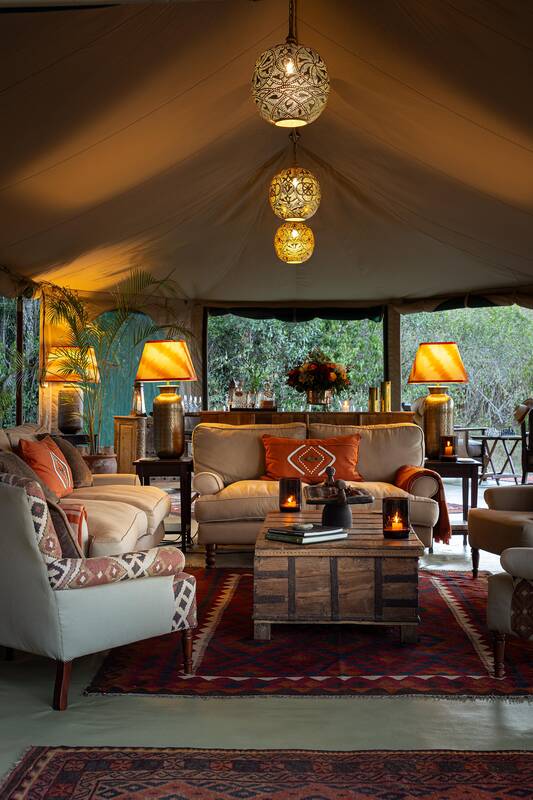 The mess lounge — sofas, lamps and brass lanterns, open to the bush