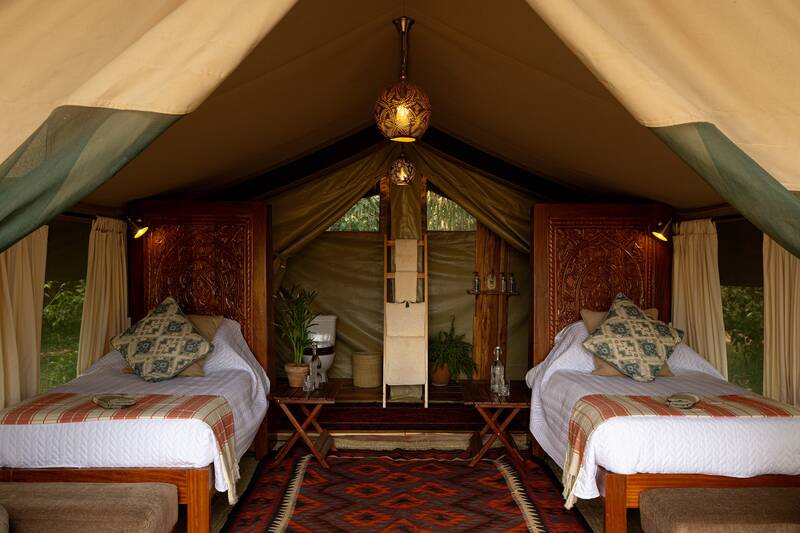 Twin beds in a Seringet tent, kilim rugs and lantern light
