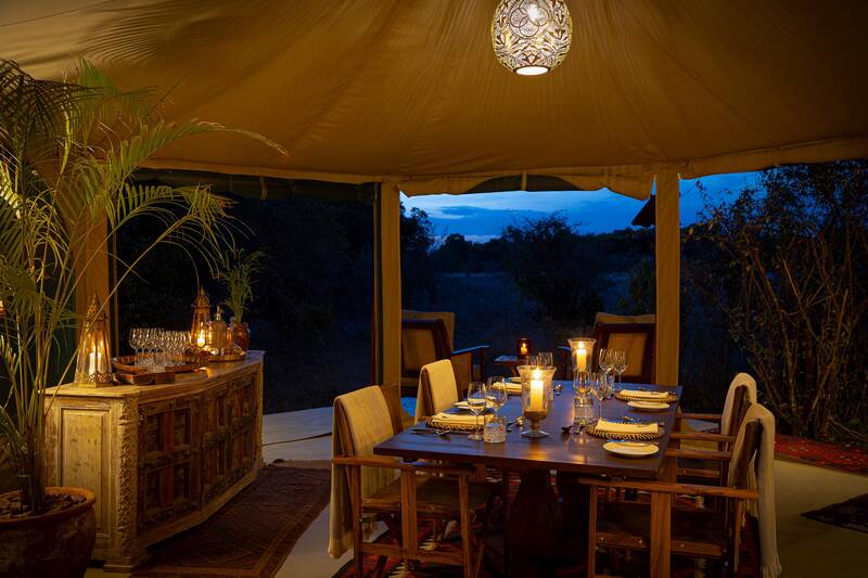Dinner laid at dusk, the Mara darkening outside the canvas