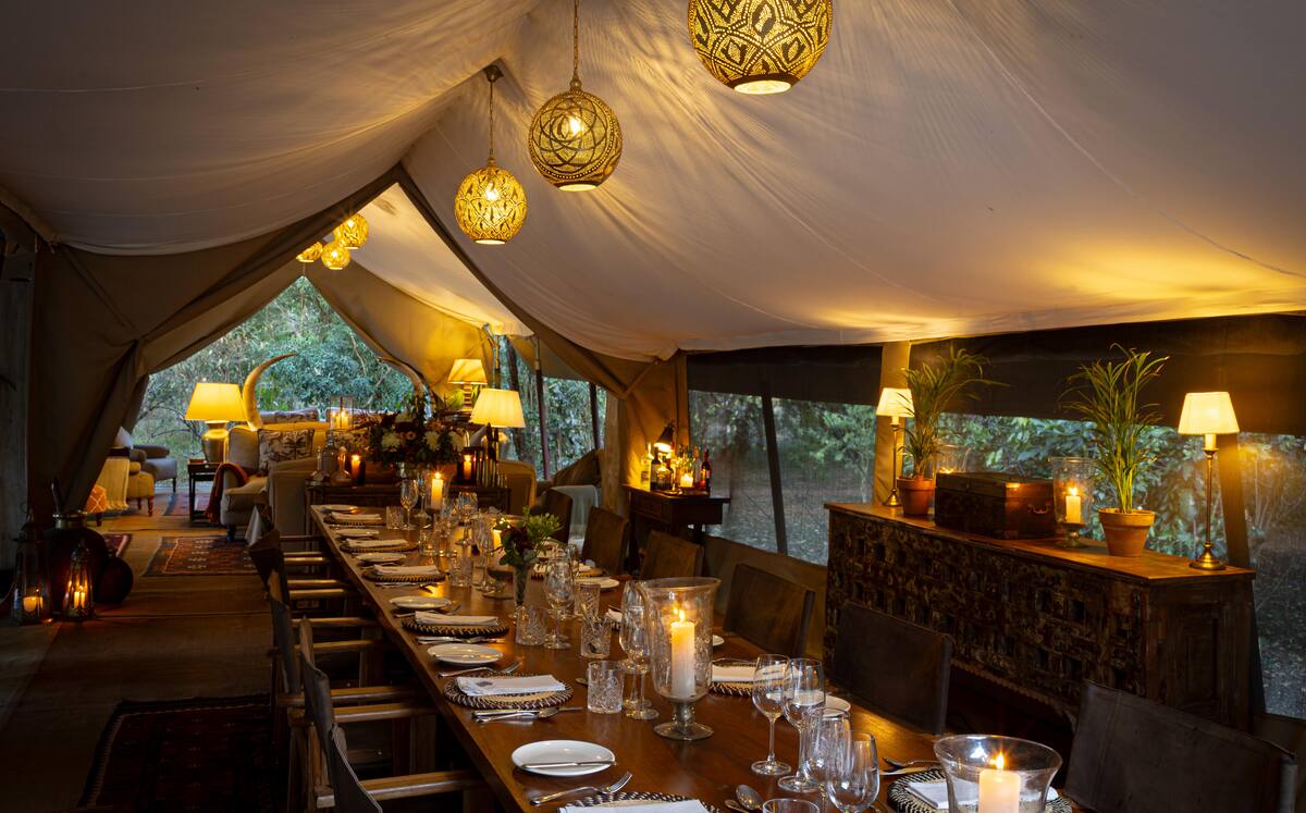 The long mess table at Seringet, laid for dinner by candle and lantern light