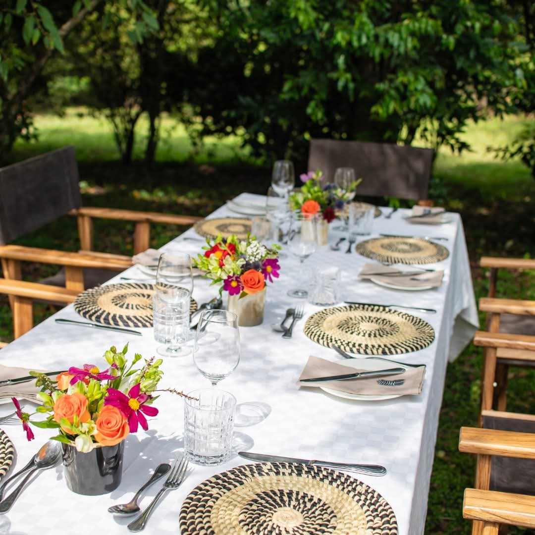 One long dining table at Seringet Mara Camp, laid with flowers and candles for dinner