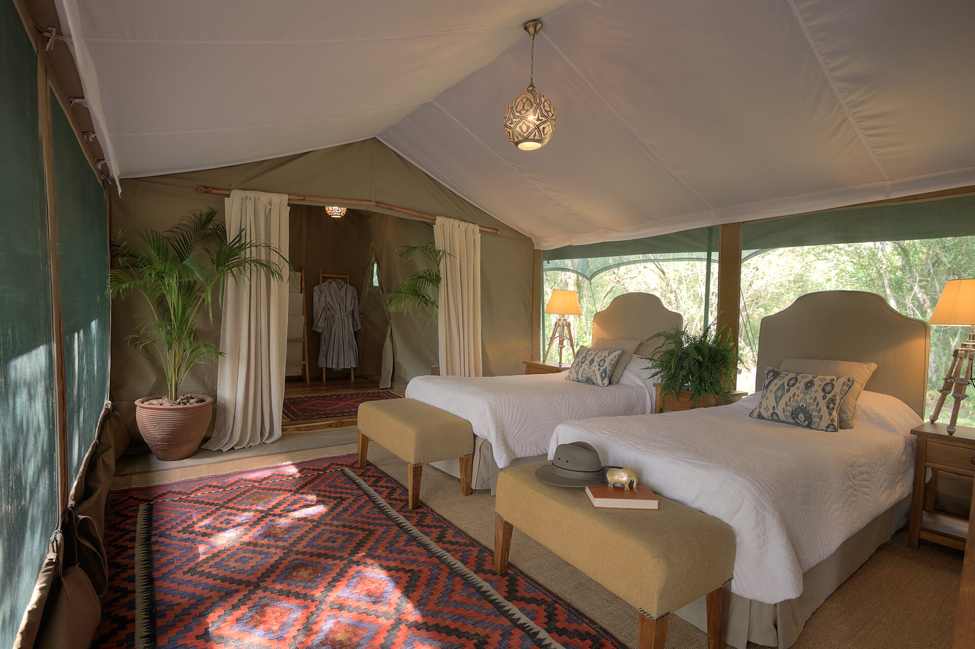 The children's side of a Seringet family suite — twin beds, kilim rug, view onto the plain