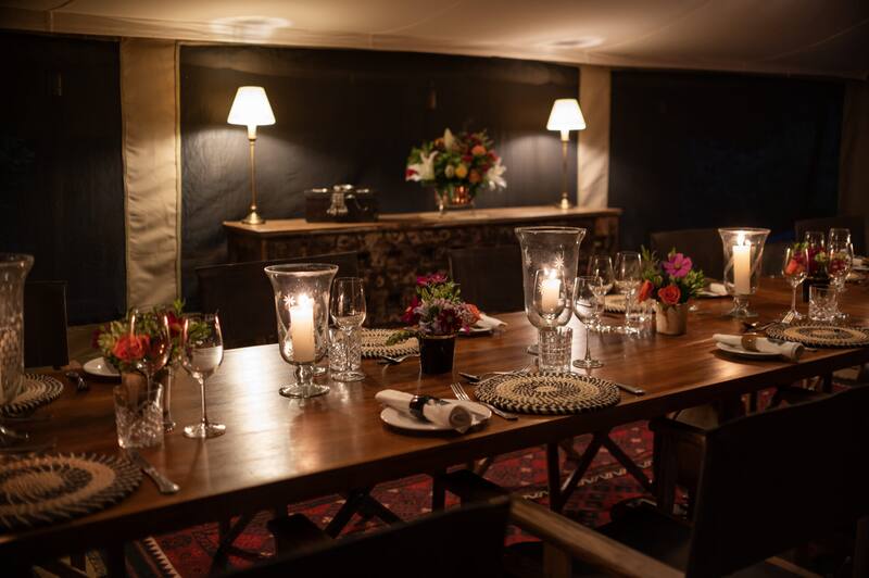 Dining set on the long mess table — candles, flowers, glassware at night